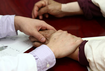 자생한방병원 자생치료의 특징-환자 손을 잡아 건강상태를 체크 하고 있는 의사의 모습